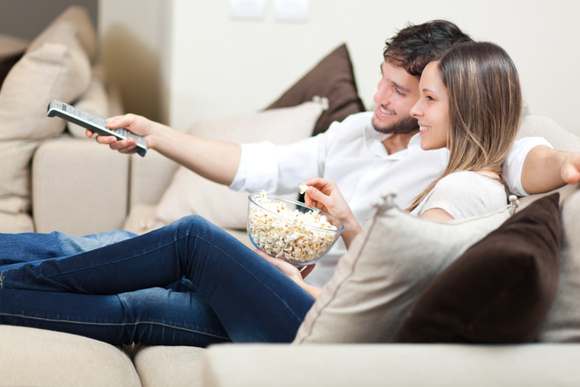 Happy young couple watching television together at home